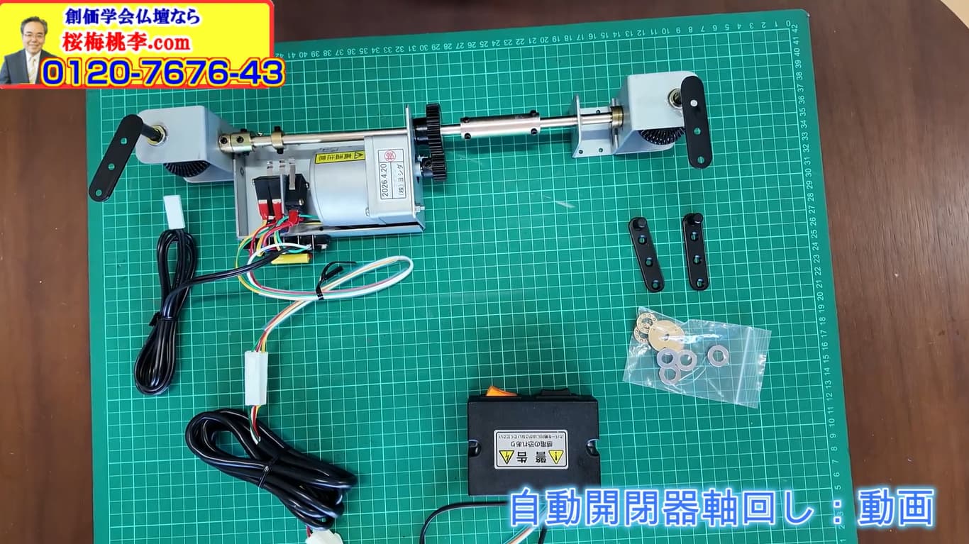 Motorized actuator with rotating shaft and end blocks on a green cutting mat, with wires, control box, and hardware kit.