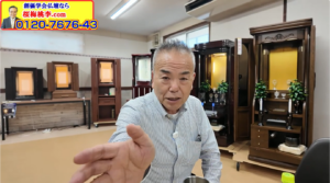 Man in a striped shirt reaching toward the camera in a showroom filled with tall wooden Buddhist altars; a bright yellow ad banner with a phone number sits in the top-left corner.