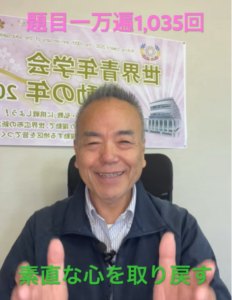 Smiling man seated in a chair in front of a banner, giving a double thumbs-up; green caption at bottom says 素直な心を取り戻す.