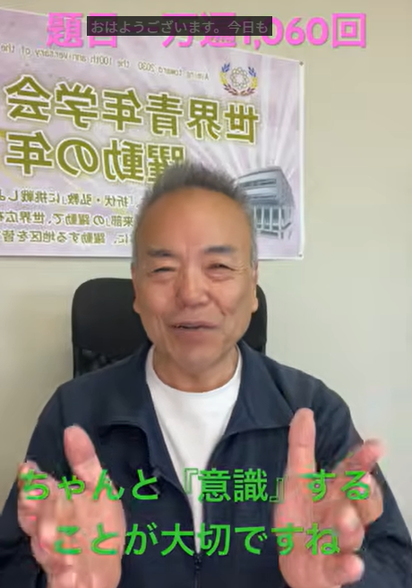 Smiling man seated in an office, gesturing with his hands, with a banner behind him and pink caption text at the top and green caption text at the bottom saying it’s important to be mindful.