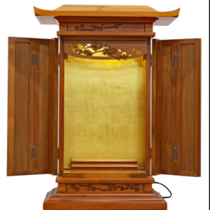 Traditional wooden altar with open doors, gold-toned inner panel, and floral carvings on the frame.