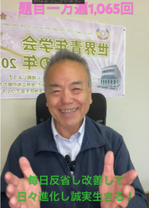 Smiling older man in an office chair with hands raised; banner behind him and pink header text '題目一万遍1,065回', green caption at bottom reads '毎日反省し改善して日々進化し誠実生きる！'