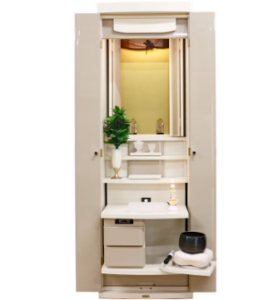 Open tall white vanity cabinet with mirror and interior light, showing shelves, a potted plant, and small grooming items arranged as a compact vanity.