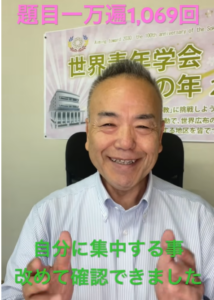 Smiling man in a light blue striped shirt sits in an office chair; pink Japanese headline is visible above and green caption below reads '自分に集中する事 改めて確認できました'.