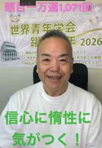 Smiling man in a white shirt sits in front of a banner with Japanese text and the year 2026.