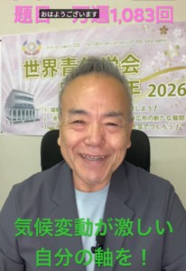 Smiling man in a blazer recording a video; green caption reads '気候変動が激しい 自分の軸を！' with a banner in the background.