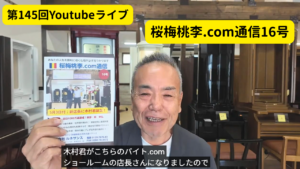 Smiling man in a showroom holds up a flyer advertising 第145回Youtubeライブ and 桜梅桃李.com通信16号.