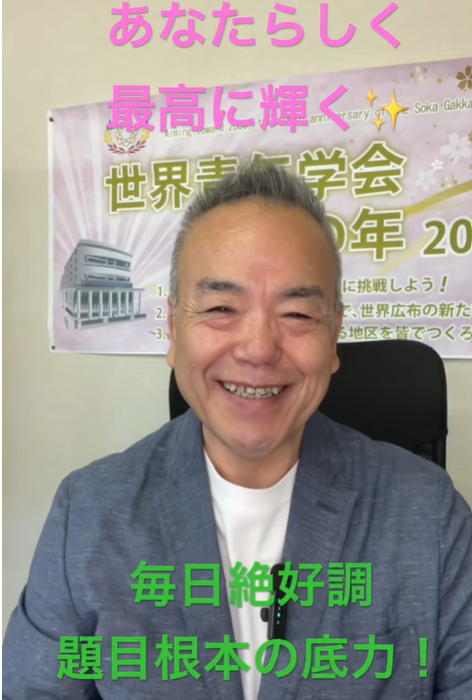 Smiling man in a blue blazer sits in front of a banner with pink and green Japanese motivational text: あなたらしく 最高に輝く and 毎日絶好調 題目根本の底力！