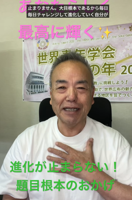 Smiling man in a white shirt seated indoors with a Japaneselanguage banner in the background; pink and green motivational text overlays appear across the image.