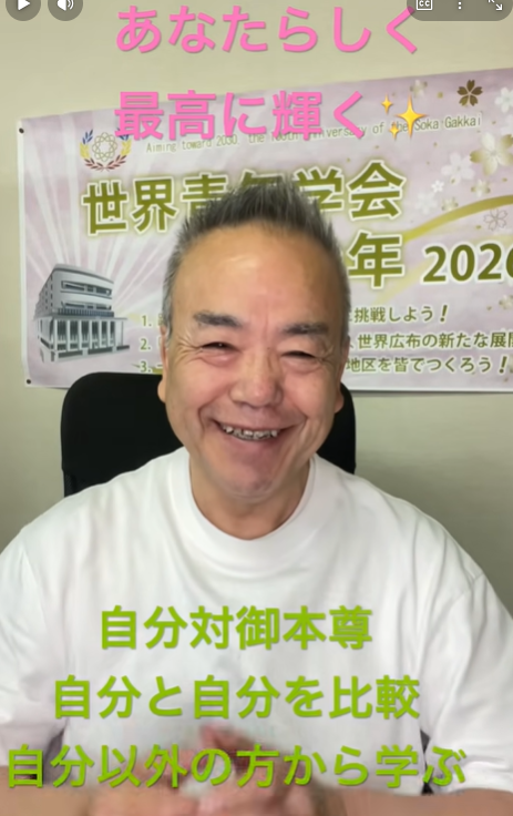 Smiling man in a white shirt sits in front of a Japanese event banner; pink and green captions are overlaid.